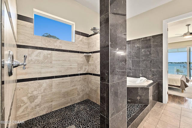 bathroom with connected bathroom, ceiling fan, a tile shower, and tile walls