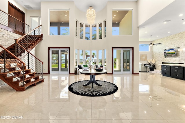 foyer with marble finish floor, stairs, ceiling fan, and a high ceiling