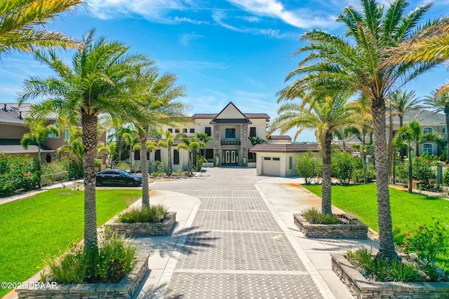 mediterranean / spanish home featuring stucco siding, an attached garage, driveway, and a front lawn