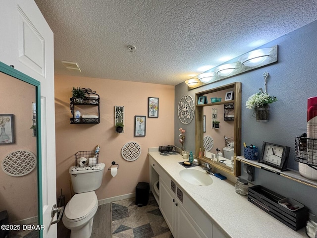 bathroom featuring baseboards, toilet, vanity, and a textured ceiling