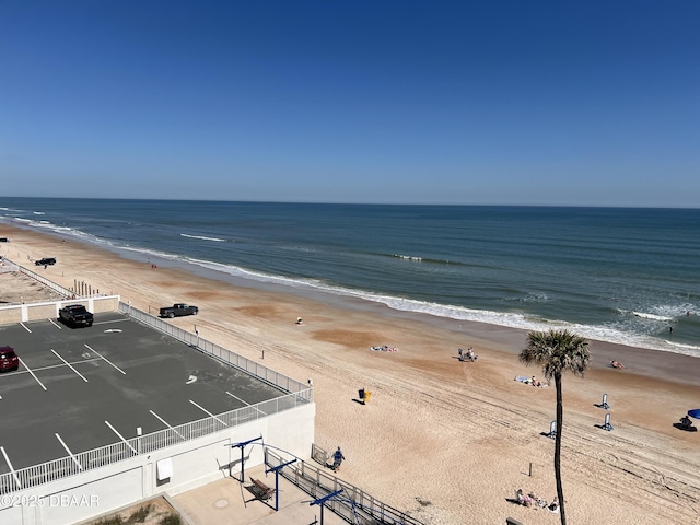 view of water feature featuring fence and a beach view