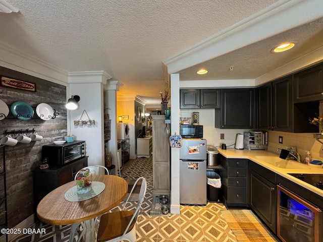 kitchen with a sink, black appliances, light countertops, a textured ceiling, and dark cabinets