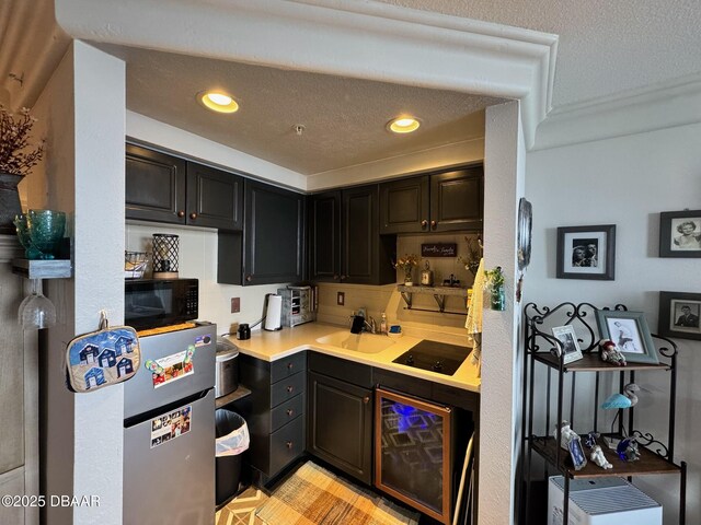 kitchen with a textured ceiling, black appliances, light countertops, and a sink