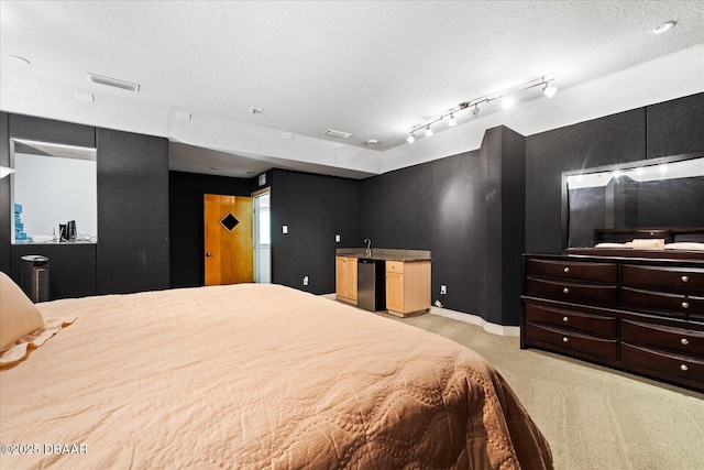 bedroom featuring visible vents, light colored carpet, a textured ceiling, and wet bar