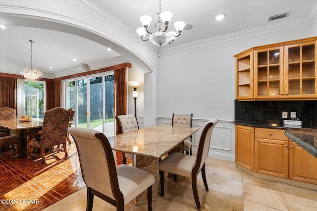 dining room with visible vents, arched walkways, wainscoting, crown molding, and a chandelier