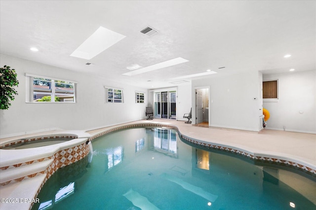 view of swimming pool featuring a skylight and a pool with connected hot tub