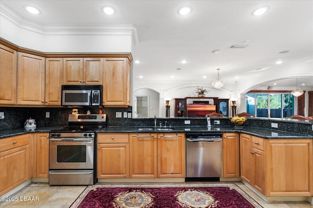 kitchen featuring stainless steel appliances, arched walkways, a sink, and ornamental molding