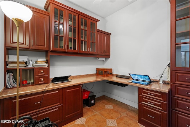 office featuring light tile patterned flooring, built in desk, and baseboards