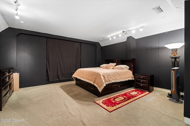 bedroom with lofted ceiling, track lighting, visible vents, and carpet flooring