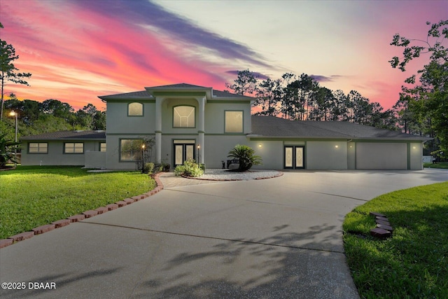 view of front of house with a garage, concrete driveway, a yard, and stucco siding