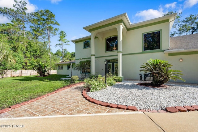 view of front of property with fence, a front lawn, and stucco siding