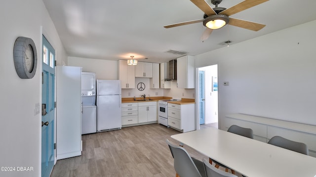 kitchen with light wood-type flooring, sink, white cabinetry, stacked washer and dryer, and white appliances