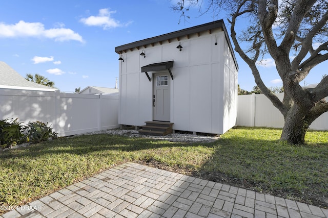 view of outdoor structure featuring entry steps, an outdoor structure, and a fenced backyard