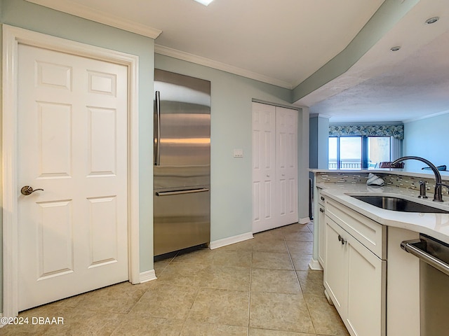 kitchen with ornamental molding, stainless steel appliances, light tile patterned floors, sink, and white cabinets