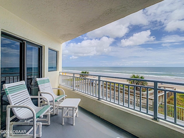 balcony featuring a water view and a beach view