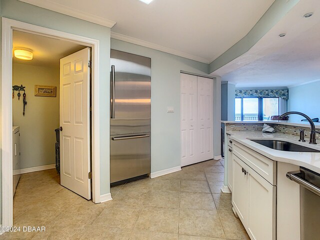 kitchen featuring stainless steel appliances, sink, ornamental molding, light tile patterned floors, and white cabinets