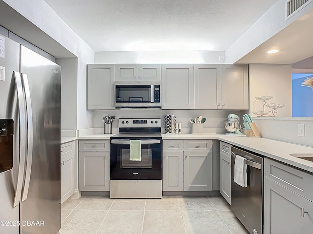 kitchen with light countertops, appliances with stainless steel finishes, visible vents, and gray cabinetry