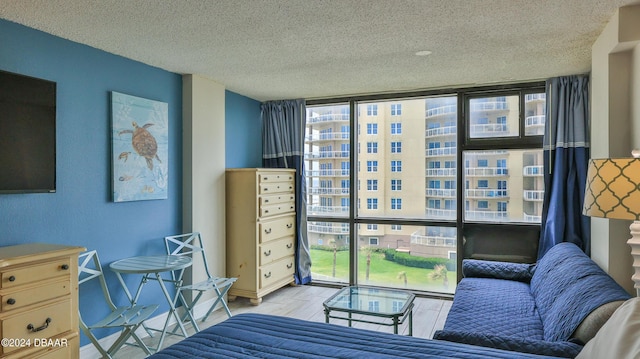 bedroom featuring floor to ceiling windows, multiple windows, light hardwood / wood-style floors, and a textured ceiling