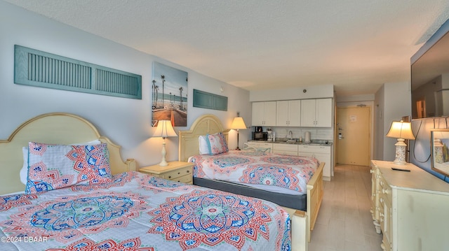 bedroom with sink, light hardwood / wood-style floors, and a textured ceiling