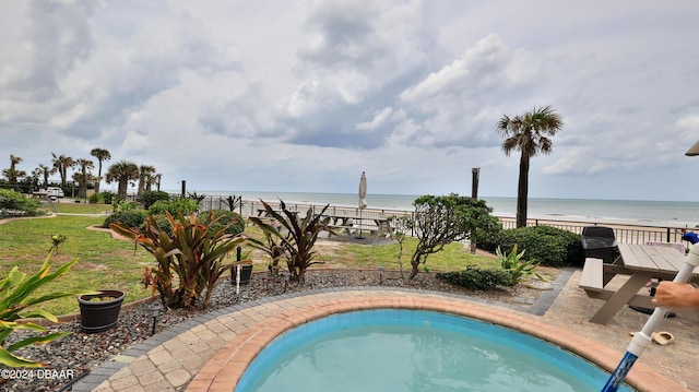 view of swimming pool with a beach view and a water view