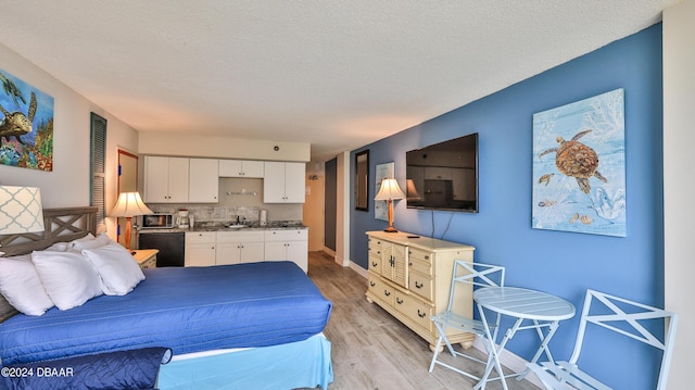 bedroom featuring light hardwood / wood-style floors, sink, and a textured ceiling