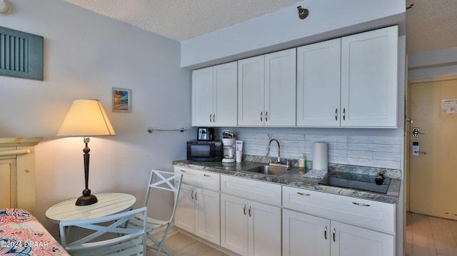 kitchen featuring backsplash, sink, white cabinets, and black appliances