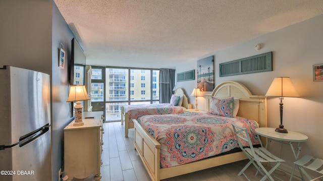 bedroom featuring stainless steel fridge, a textured ceiling, and expansive windows