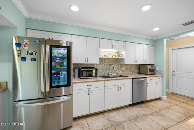 kitchen featuring appliances with stainless steel finishes, sink, white cabinets, and decorative backsplash