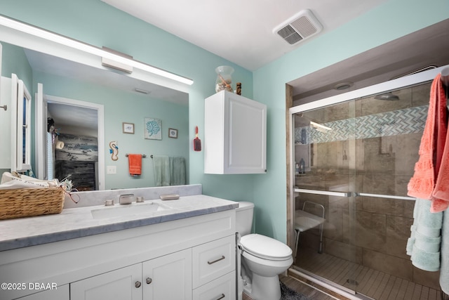 bathroom featuring vanity, a shower with door, and toilet