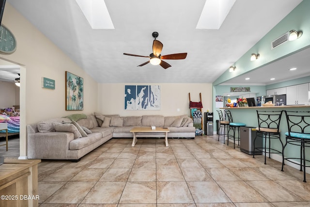 living room featuring ceiling fan and vaulted ceiling with skylight