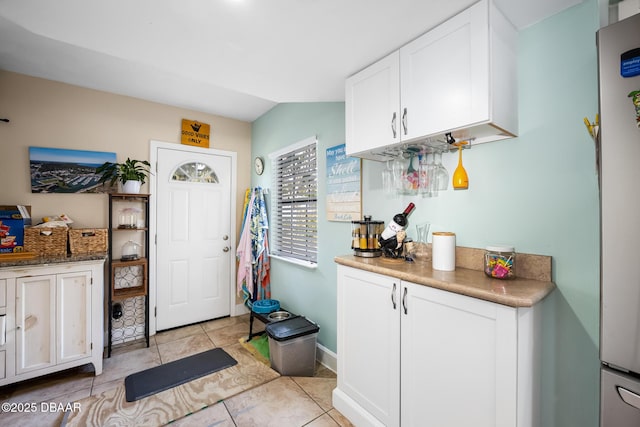 kitchen featuring refrigerator, light tile patterned floors, and white cabinets