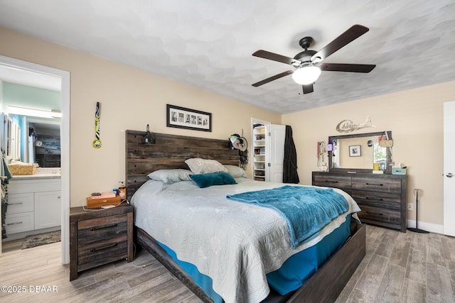 bedroom with light hardwood / wood-style floors, ceiling fan, and ensuite bath