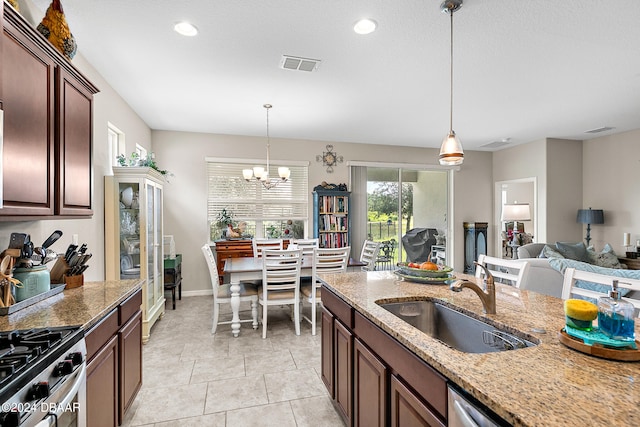 kitchen featuring light tile patterned flooring, sink, light stone countertops, hanging light fixtures, and a notable chandelier