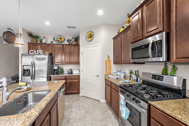 kitchen featuring light tile patterned flooring, sink, appliances with stainless steel finishes, light stone countertops, and pendant lighting