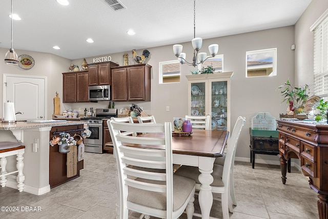 kitchen with a wealth of natural light, appliances with stainless steel finishes, decorative light fixtures, and a breakfast bar area