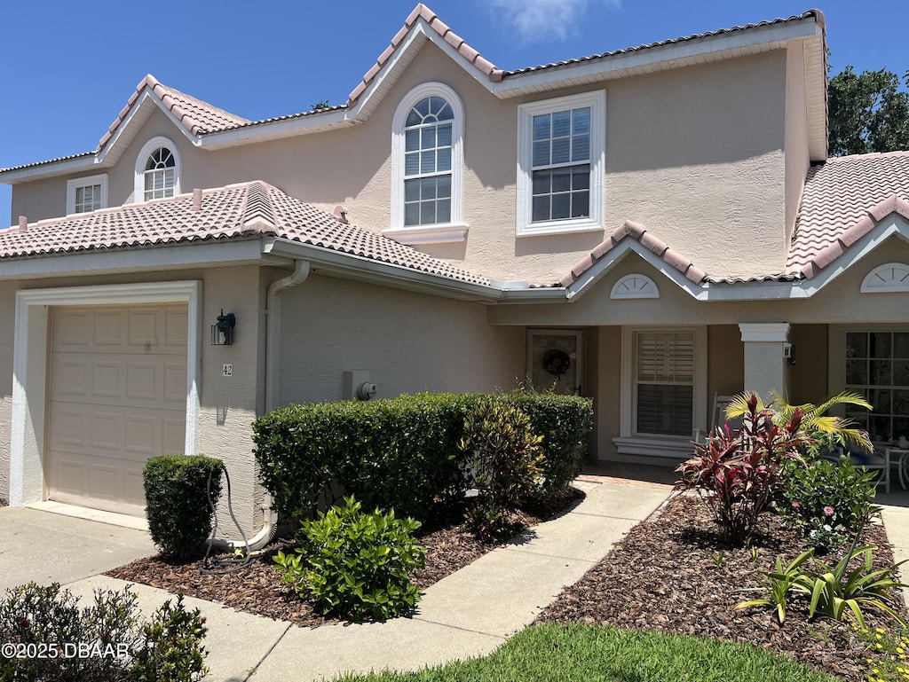view of front of property featuring stucco siding, an attached garage, and a tile roof