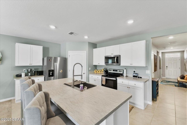 2714 Neverland Dr, New Smyrna Beach, FL 32168 - kitchen with appliances with stainless steel finishes, light countertops, an island with sink, white cabinetry, and recessed lighting