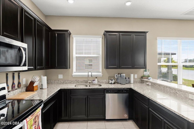 2916 Meleto Blvd, New Smyrna Beach, FL 32168 - kitchen with appliances with stainless steel finishes, a sink, dark cabinetry, light tile patterned floors, and light stone counters