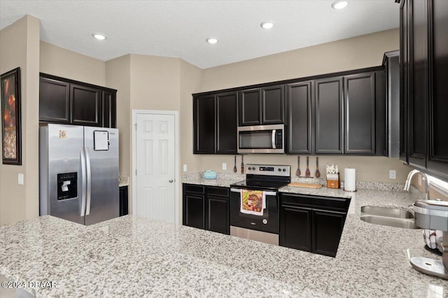 2916 Meleto Blvd, New Smyrna Beach, FL 32168 - kitchen with stainless steel appliances, a sink, dark cabinets, light stone counters, and recessed lighting