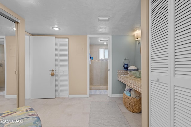 bathroom with a textured ceiling and tile patterned floors