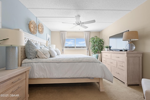 bedroom featuring ceiling fan, light colored carpet, and a textured ceiling