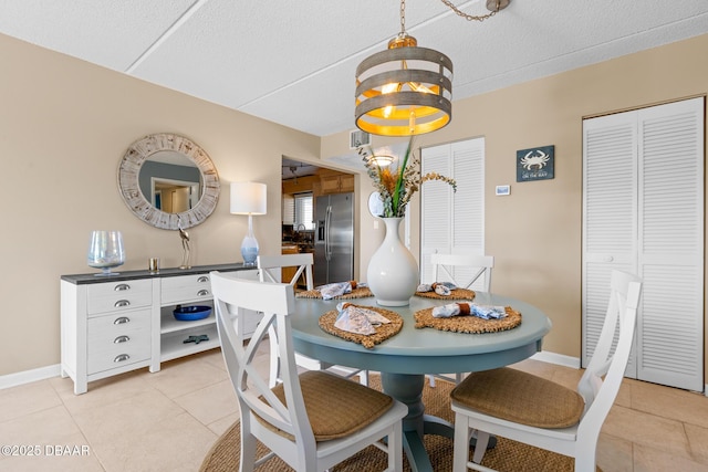 tiled dining room with a textured ceiling and a chandelier