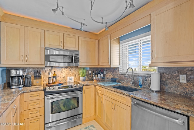 kitchen with light brown cabinetry, rail lighting, stainless steel appliances, sink, and stone counters