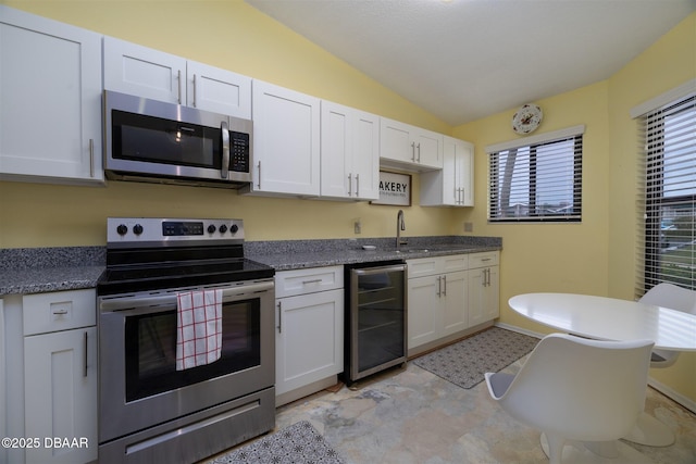 kitchen with a sink, white cabinetry, stainless steel appliances, beverage cooler, and lofted ceiling