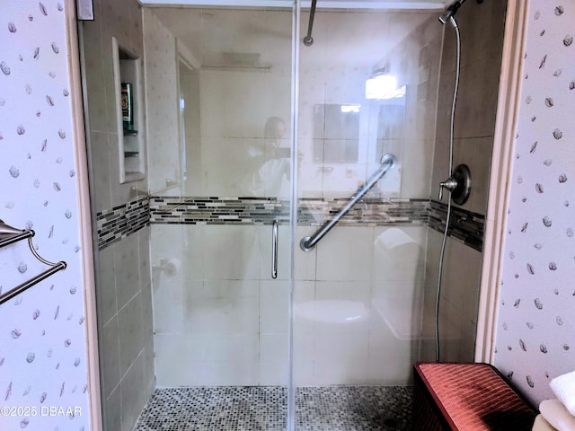 bathroom featuring a shower stall and wallpapered walls