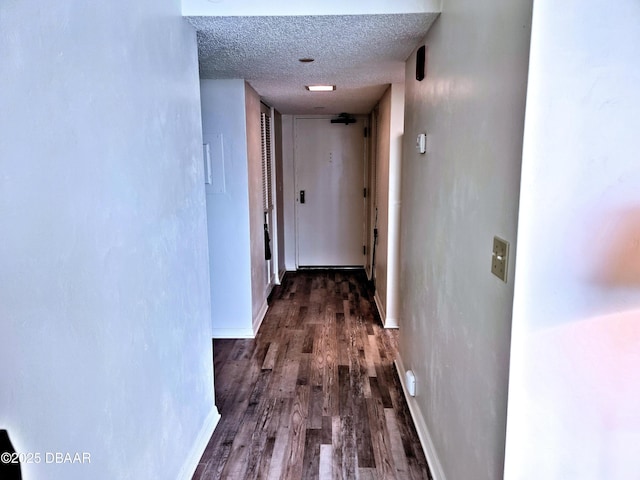 hall featuring baseboards, a textured ceiling, and dark wood-style flooring