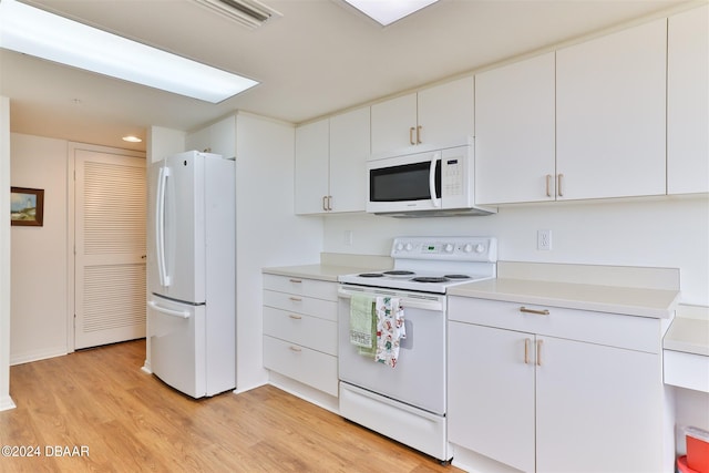 kitchen featuring white cabinets, light wood-type flooring, and white appliances