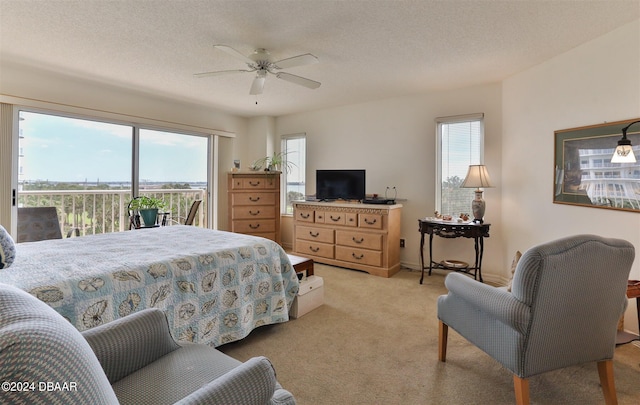 bedroom featuring access to exterior, a textured ceiling, light carpet, and ceiling fan