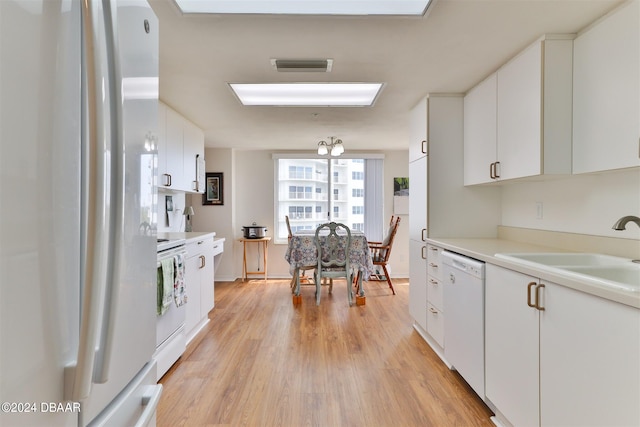 kitchen with white cabinets, light hardwood / wood-style flooring, sink, and white appliances