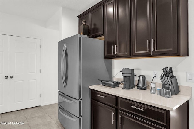 kitchen featuring stainless steel fridge, dark brown cabinets, and light tile patterned flooring